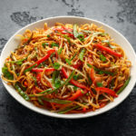 Chow mein, noodles and vegetables dish with wooden chopsticks.